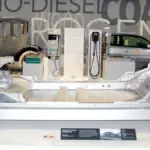 Exposed structural chassis of an electric passenger vehicle displaying the sealed underfloor traction battery compartment and electric motor drives.