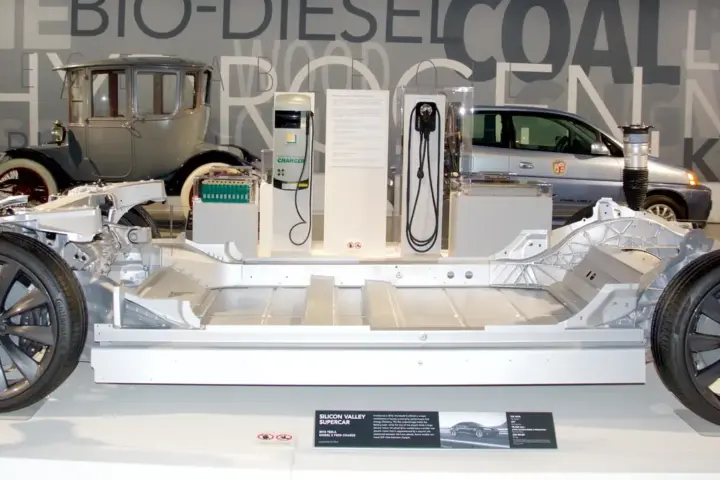 Exposed structural chassis of an electric passenger vehicle displaying the sealed underfloor traction battery compartment and electric motor drives.