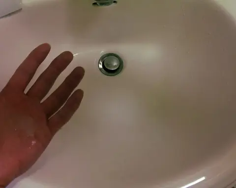 Liquid hand soap beside a bathroom sink
