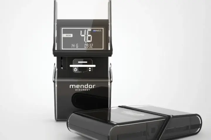 Photograph of a digital blood glucose meter with a test strip and detachable components on a white background.