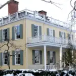Exterior front facade of Gracie Mansion surrounded by trees and snow in Manhattan’s Carl Schurz Park.