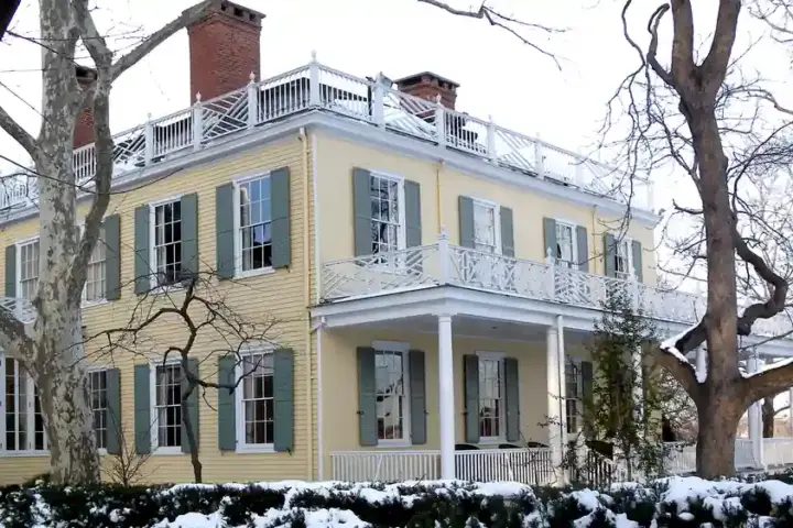 Exterior front facade of Gracie Mansion surrounded by trees and snow in Manhattan’s Carl Schurz Park.