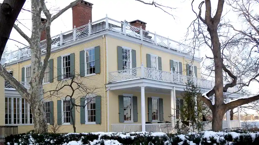 Exterior front facade of Gracie Mansion surrounded by trees and snow in Manhattan’s Carl Schurz Park.