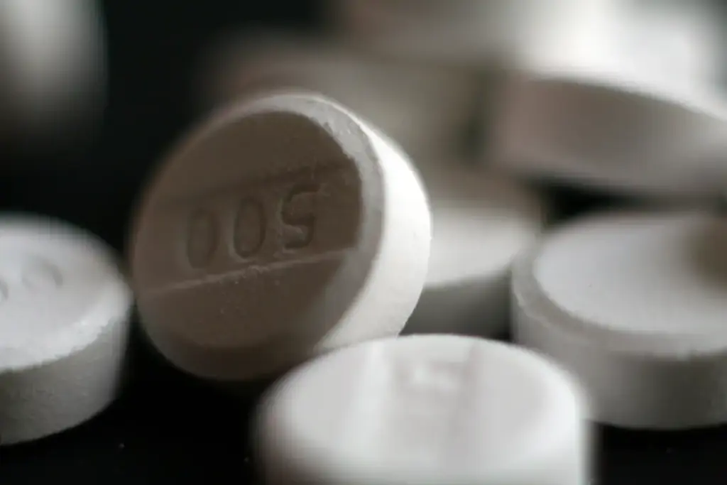 Close-up photograph of white pharmaceutical acetaminophen 500 milligram tablets on a neutral surface