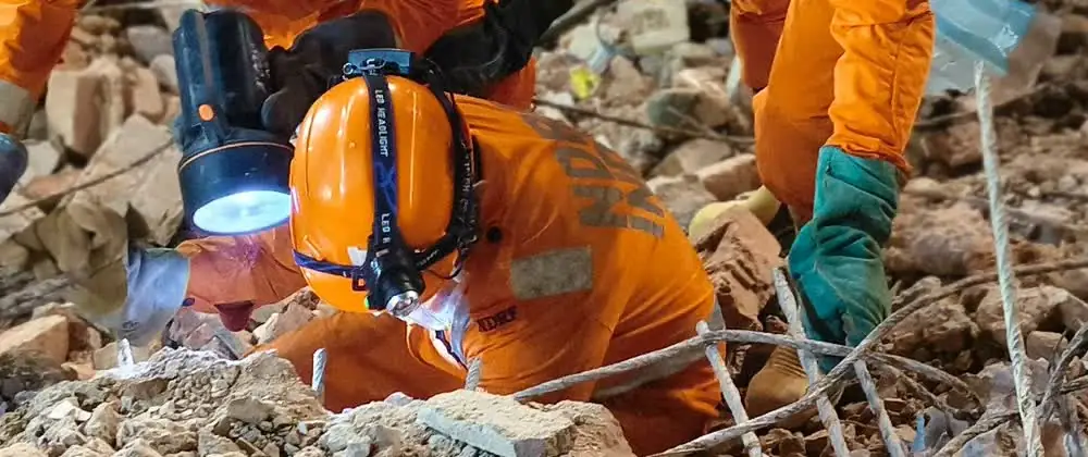 NDRF rescuers search through rubble after the Satya Niketan building collapse in Delhi.
