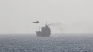 Commercial tanker moving through hazy waters with smoke visible from its stack