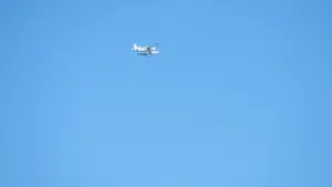 A Cessna 208 Caravan aircraft flying over coastal water, representing the type of turboprop aircraft used in autonomous flight testing like Joby's cross-US demonstration.