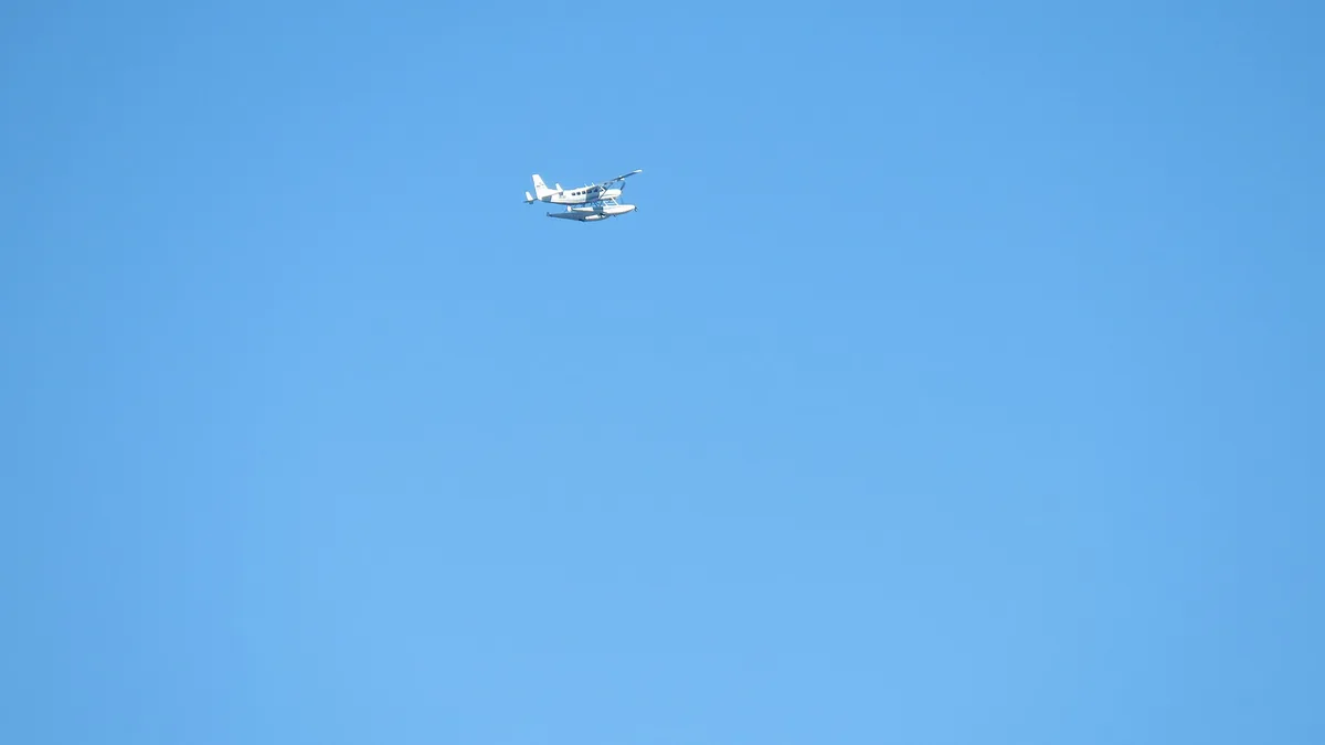 Cessna 208 Caravan aircraft flying over coastal water during approach