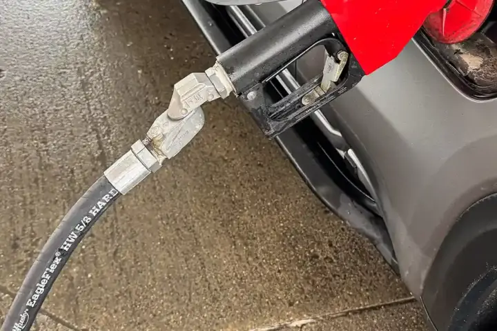 Fuel nozzle inserted into a car during refilling at a petrol station