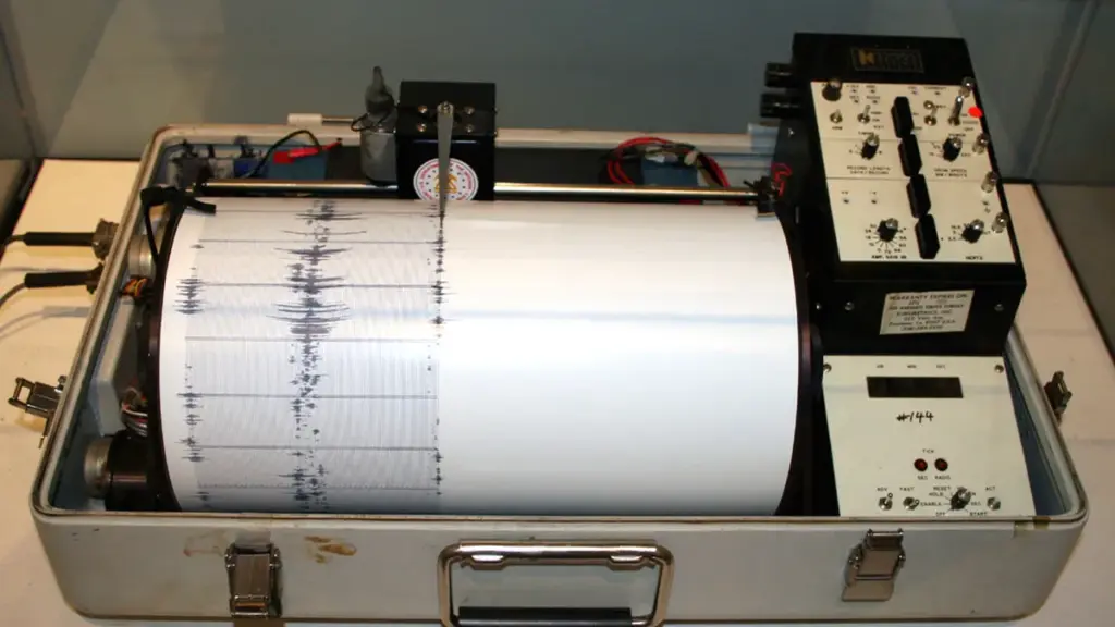 Analog rotating seismograph drum with stylus recording seismic waveform lines on paper