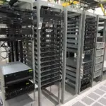 Server cabinet racks with illuminated status indicators and network cabling in a data facility