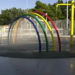 Outdoor community splash pad and interactive water spray feature in a public park