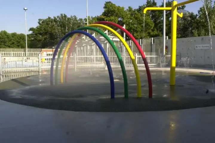 Outdoor community splash pad and interactive water spray feature in a public park