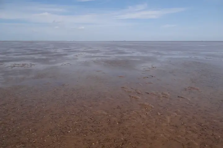 Expansive coastal mudflats and shallow waters at low tide along The Wash coastline bordering Norfolk and Lincolnshire.