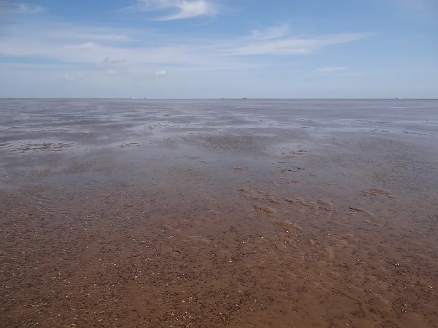 Expansive coastal mudflats and shallow waters at low tide along The Wash coastline bordering Norfolk and Lincolnshire.