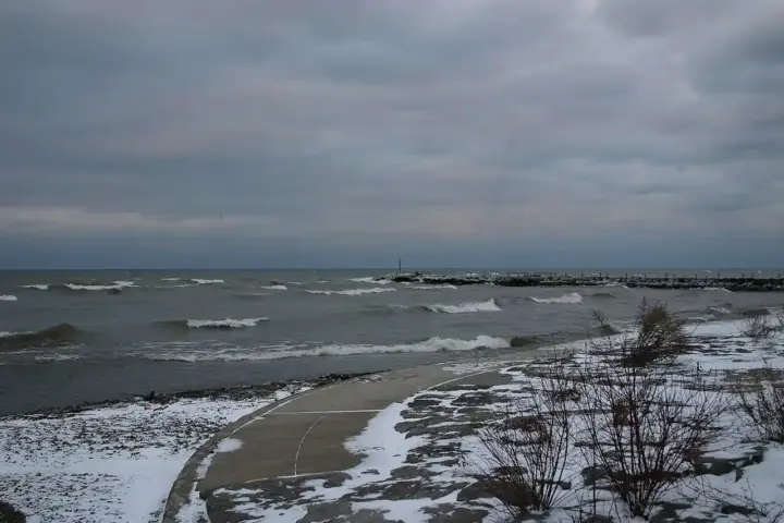 Wide-angle photograph of the open waters and natural coastline of Lake Ontario under an open sky.