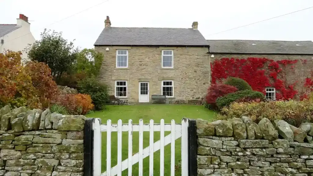 Garden gate beside a stone wall and green space in an English village