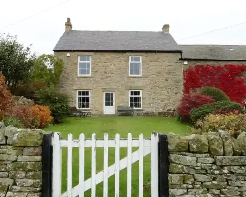Garden gate beside a stone wall and green space in an English village