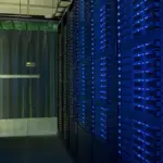 Racks of network servers and glowing fiber-optic cabling in a high-density enterprise data center.