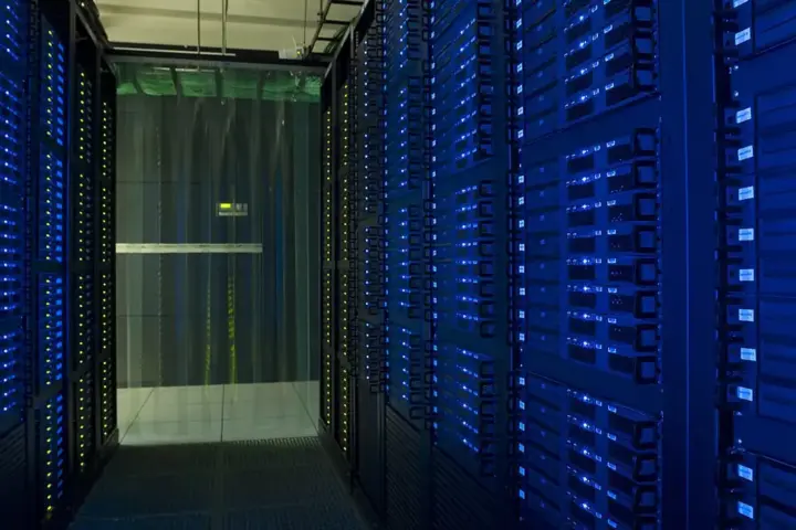 Racks of network servers and glowing fiber-optic cabling in a high-density enterprise data center.