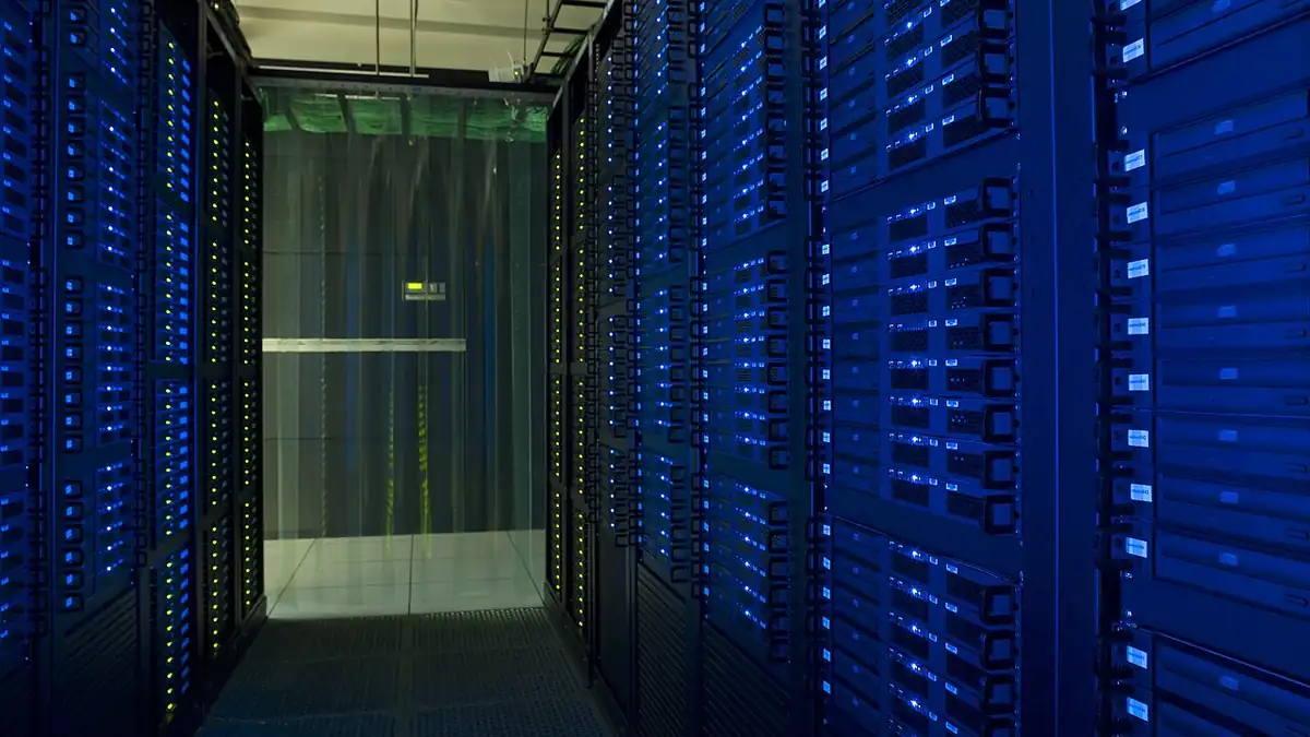 Racks of network servers and glowing fiber-optic cabling in a high-density enterprise data center.