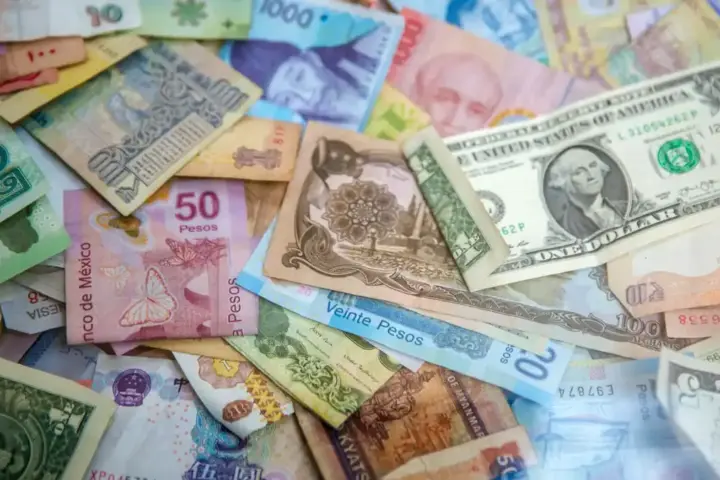 U.S. dollar and Mexican peso banknotes placed together to illustrate currency exchange rates.