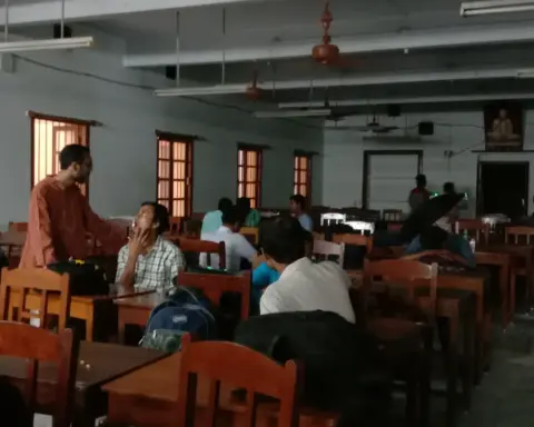 Group of Indian students seated at wooden study desks inside an academic classroom setting.