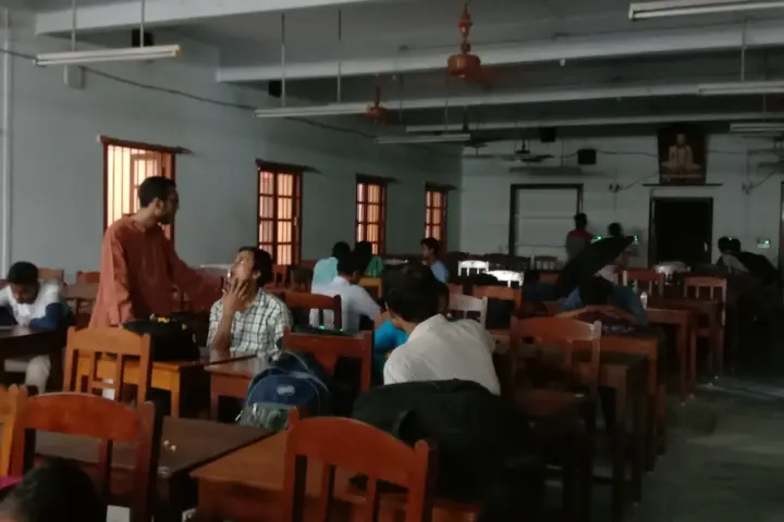Group of Indian students seated at wooden study desks inside an academic classroom setting.