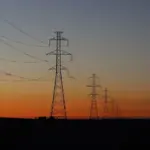Electric transmission lines crossing the sky, used as a representative image for utility bill assistance.