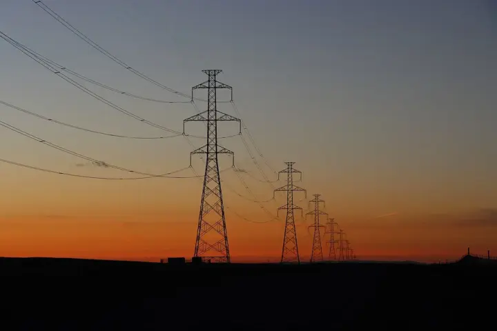 Electric transmission lines crossing the sky, used as a representative image for utility bill assistance.