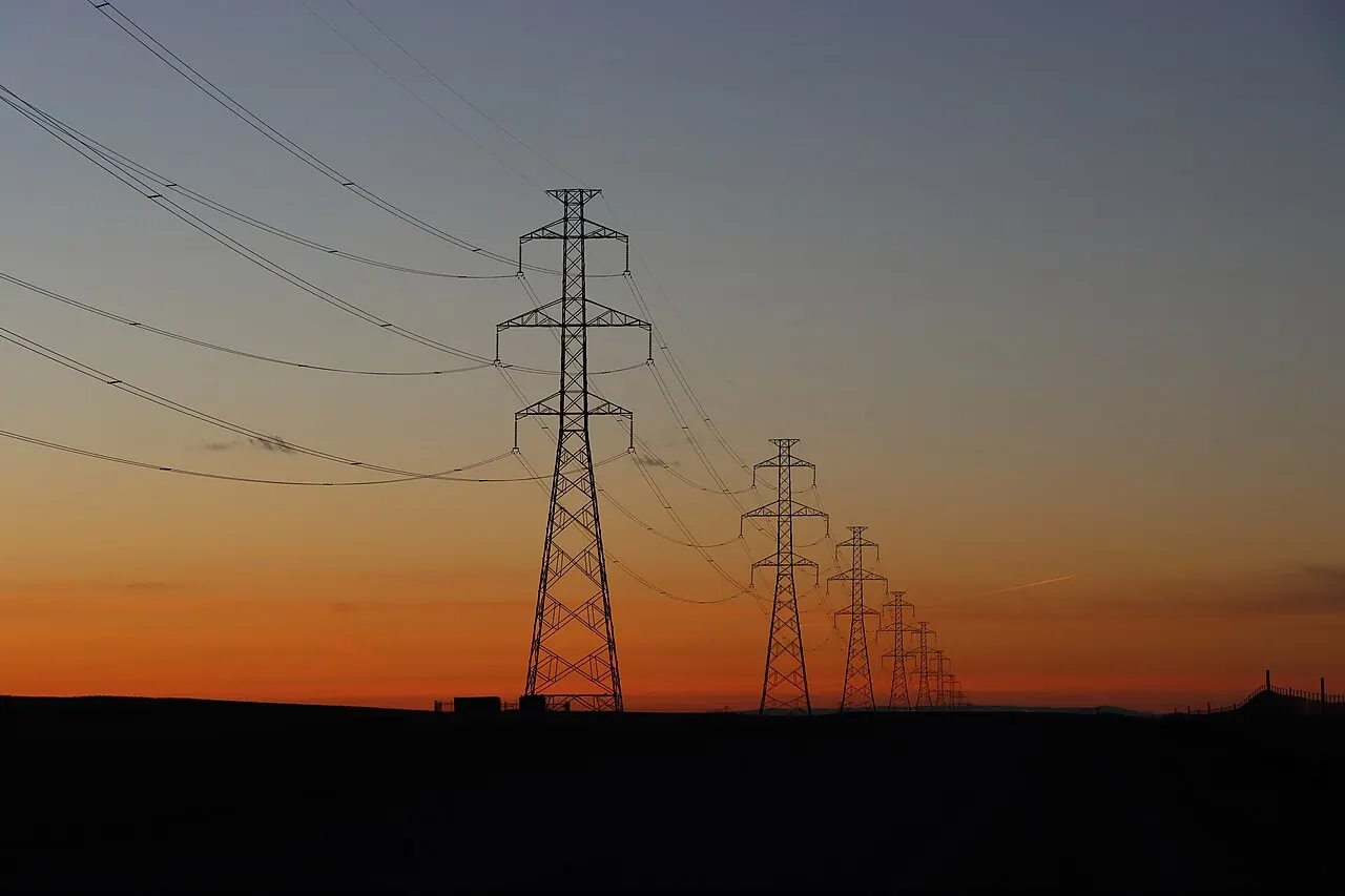 Electric transmission lines crossing the sky, used as a representative image for utility bill assistance.