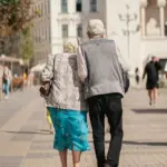 An older couple walks together on a city pavement, representing pensioners weighing the Winter Fuel Payment opt-out deadline.
