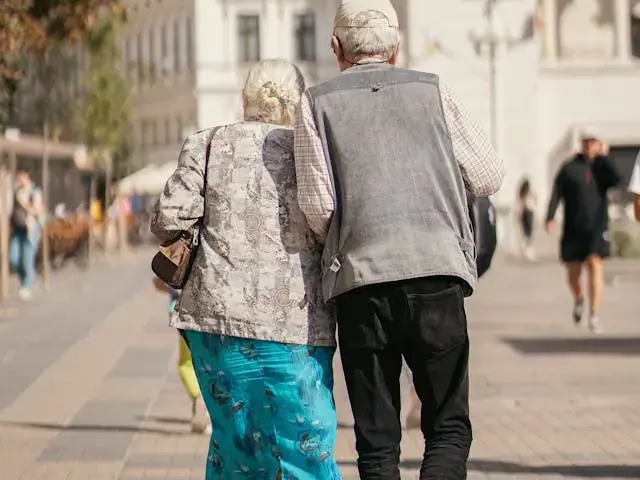 An older couple walks together on a city pavement, representing pensioners weighing the Winter Fuel Payment opt-out deadline.