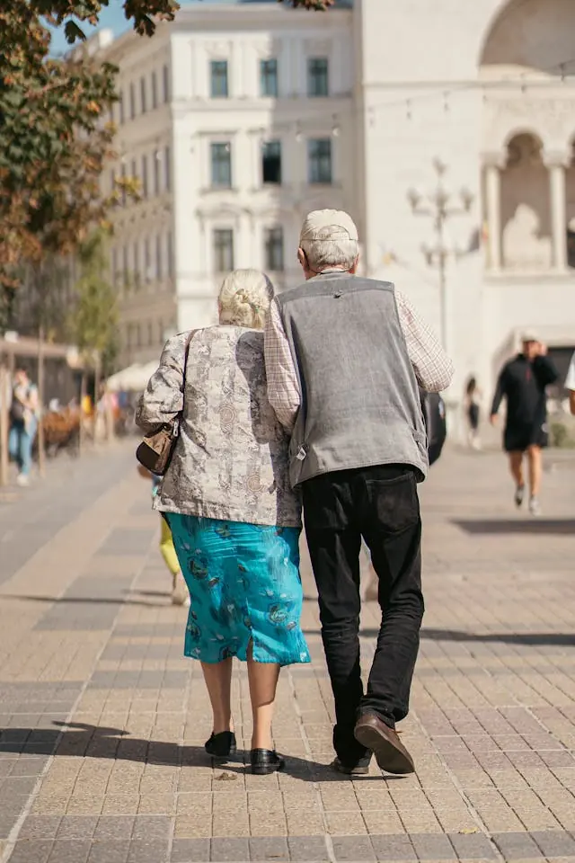 An older couple walks together on a city pavement, representing pensioners weighing the Winter Fuel Payment opt-out deadline.