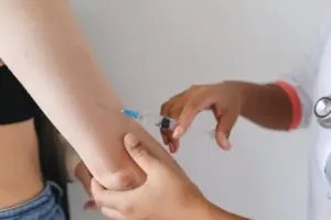 A healthcare worker administers an injection, representing clinical research into one-time cholesterol-lowering gene-editing treatment.