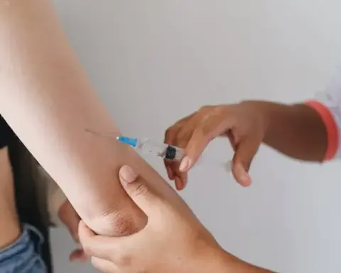 A healthcare worker administers an injection, representing clinical research into one-time cholesterol-lowering gene-editing treatment.