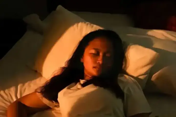 A person lies in bed with warm side lighting, representing nighttime light exposure studied for links to heart structure changes.