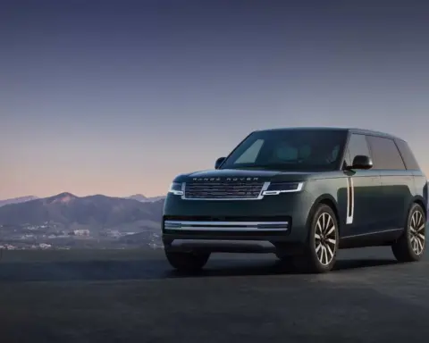 A dark metallic Range Rover Electric luxury SUV parked on a paved testing surface showing sleek aerodynamics and sealed front grille.