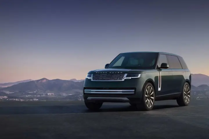 A dark metallic Range Rover Electric luxury SUV parked on a paved testing surface showing sleek aerodynamics and sealed front grille.