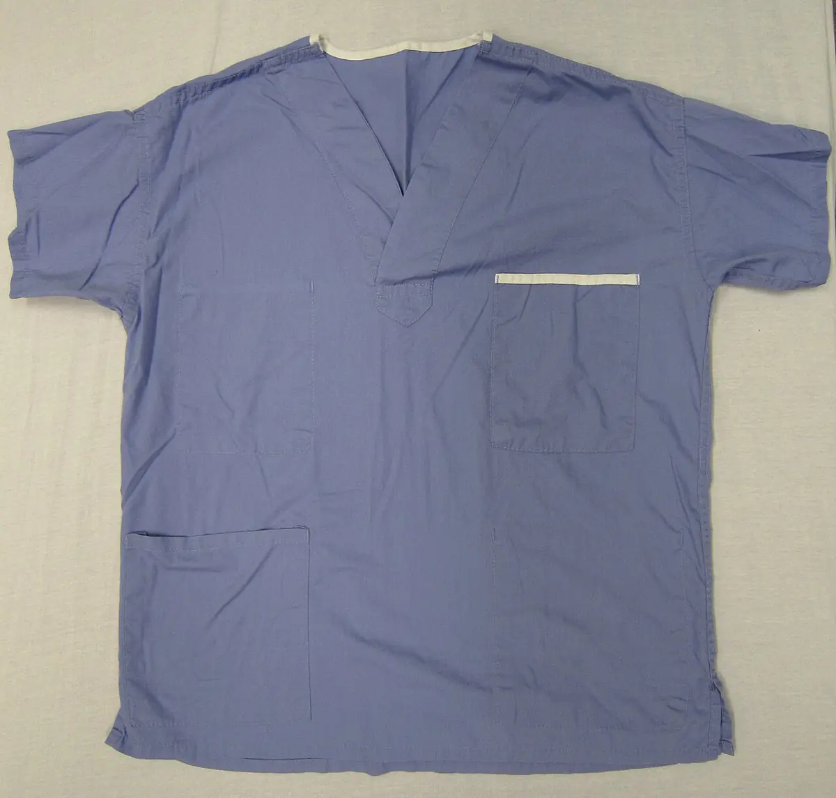 Blue medical scrub top photographed on a plain surface