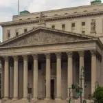 The classical granite colonnade and pediment of the New York County Supreme Courthouse in lower Manhattan.
