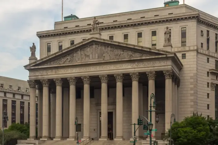 The classical granite colonnade and pediment of the New York County Supreme Courthouse in lower Manhattan.
