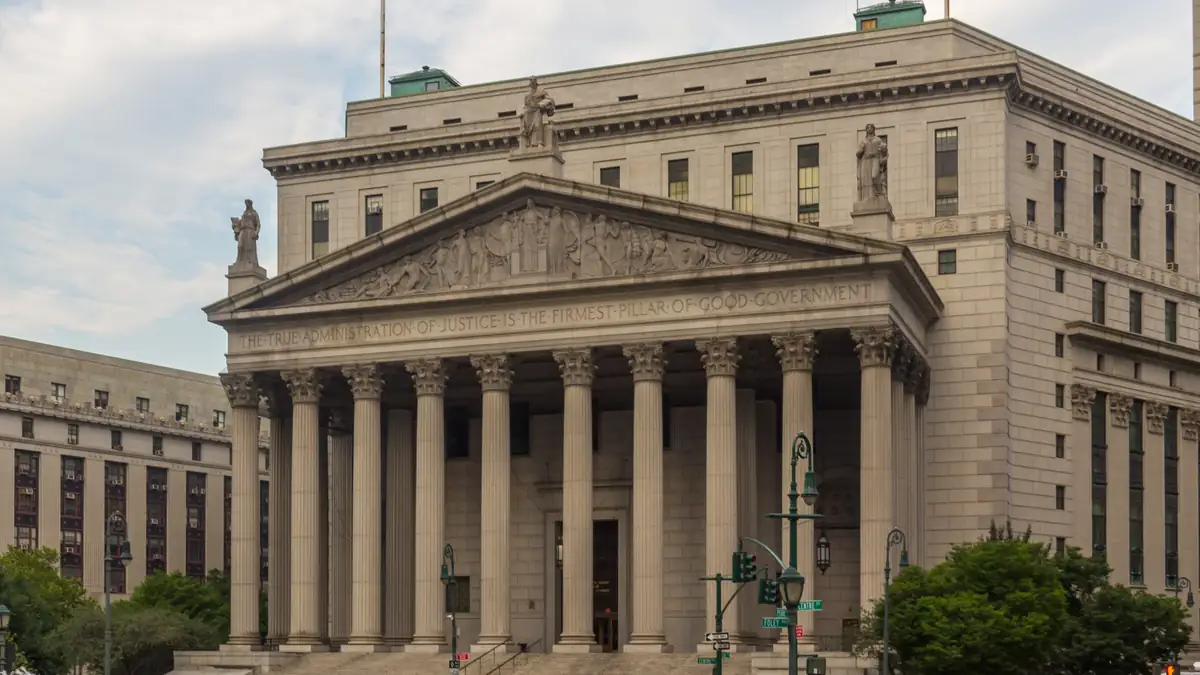 The classical granite colonnade and pediment of the New York County Supreme Courthouse in lower Manhattan.