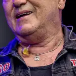 Angry Anderson performing on stage with a microphone during a Rose Tattoo concert appearance.