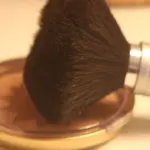 Close-up photograph of a makeup brush with cosmetic powder, representing retail beauty products.