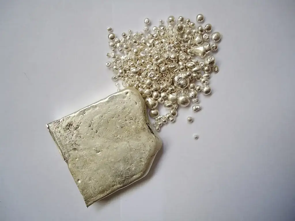 Silver ingot and fine silver granules photographed on a work surface