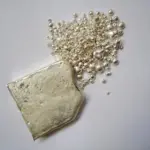 Silver ingot and fine silver granules photographed on a work surface