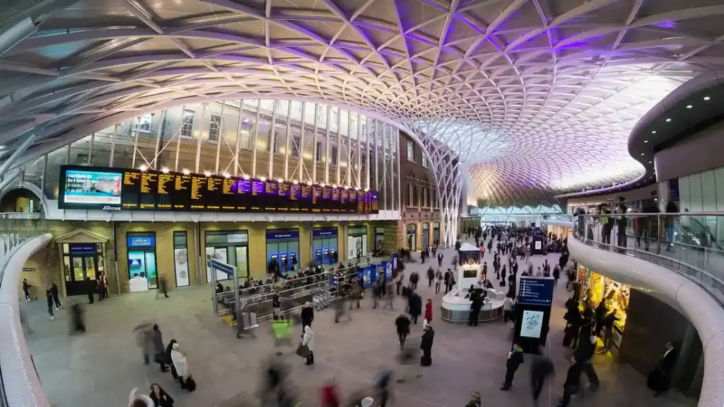 White diagrid roof and departure area inside London King’s Cross station, a major East Coast Main Line terminus.