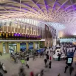 White diagrid roof and departure area inside London King’s Cross station, a major East Coast Main Line terminus.