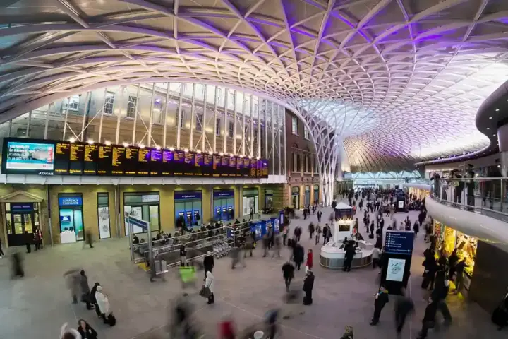 White diagrid roof and departure area inside London King’s Cross station, a major East Coast Main Line terminus.